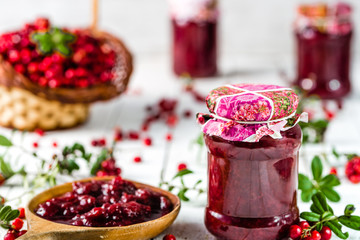 Jar of jam with berries on white table, natural organic food background