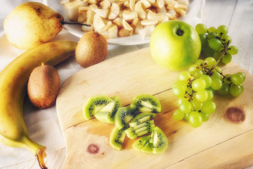 Ingredients for fruit salad. Cutting kiwi