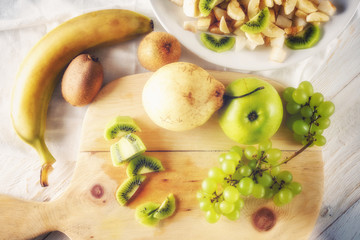 Ingredients for fruit salad. Cutting kiwi