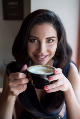 girl with a cappuccino cup in a cafe