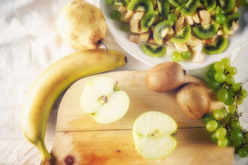 Ingredients for fruit salad. Cutting apple