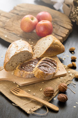French bread baguette cut on wooden board with knife. with a chocolate butter and red apple.