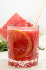 Summer drink watermelon smoothie juice in glass with cocktail tube and watermelon slice on white background. Watermelon lemon cocktail.