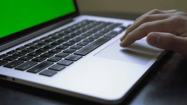 Female hands working on laptop with green screen at home. Scrolling through track pad 