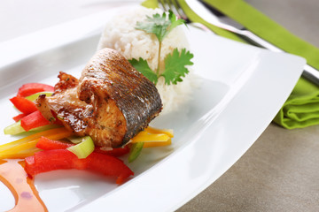 Serving plate with delicious fish, sauce, rice and vegetables on table, closeup