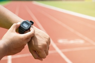 Athlete checking his watch Race timer runner ready to run on running track.