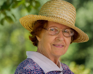 Portrait of a woman aged in glasses and a straw hat