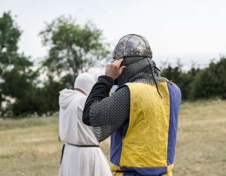 Medieval Knight Getting Ready For Battle, Reenactment With Costumed Characters And Medieval Armor With Chainmail, Helmet Swords And Shields. Medieval Demonstration And Recreation