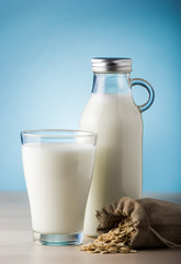 Glass of milk and sack of oats on a wooden table and blue background. daily food