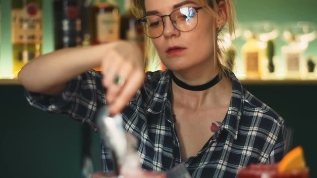 Young stylish woman bartender barmaid preparing alcoholic beverage binge cocktail night club bar portrait glasses taking granulated ice spoon orange lime straw barkeeper professional service waitress