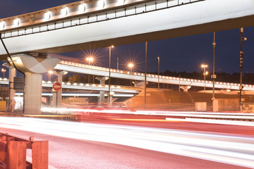 elevated road junction in the city and interchange overpass at night with motion light from cars and trucks