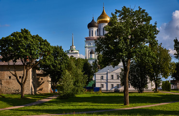 Trinity Cathedral of the Pskov Kremlin/There are clouds in the sky. For the trees you can see the domes of the Trinity Cathedral of the Pskov Kremlin, as well as the temple buildings. Russia, Pskov