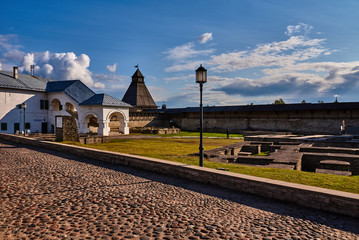Buildings of the Pskov Kremlin/The summer day. Clouds in the sky. Area of the Pskov Kremlin buildings. In the background is a wooden watchtower. Russia, Pskov region, history