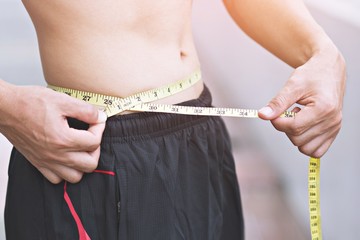 Young sporty man Check body with measuring tape outdoor.Close up, concept of healthy and sport. 