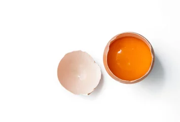 Foto auf Acrylglas egg yolk in egg shell, cracked egg white isolated on white background © antpkr