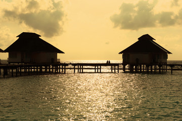 Fototapeta na wymiar Silhouette couple enjoy the moment at water villa in Maldives during sunset