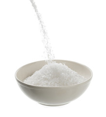 Pouring sea salt in porcelain bowl isolated on white background.   