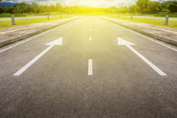 white two arrow on asphalt road with yellow light