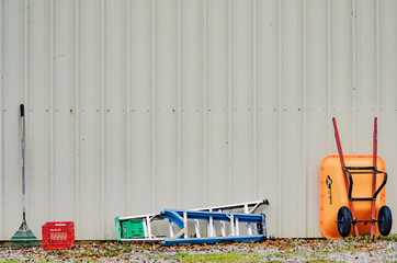 A rake, a milk crate, two ladders, and a wheelbarrow at the side of a pole barn at Talladega Gran Prix Raceway in Munford, Alabama, USA