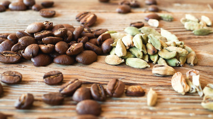 Coffee beans and cardamom on a wooden table. Rustic background