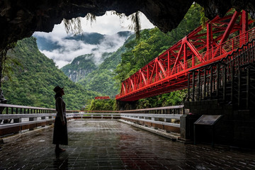 Woman looking at the red bridge in toroko national park in hualien, Taiwan
