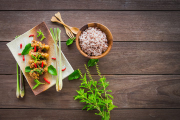 Stir-fried chicken with basil and rice on wood table