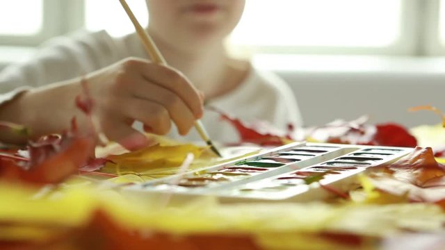 Girls draw watercolor on the autumn theme. Close-up of the diffusion of yellow paint in   water 
