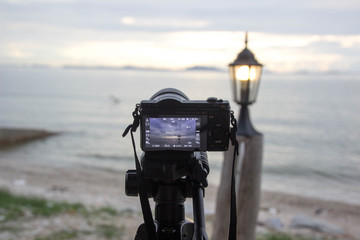 The camera is taking a picture of the sea, the lamp, the sunset at sunset.