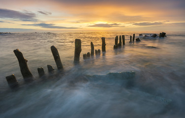 a sea breakwater breaking the waves at sunset