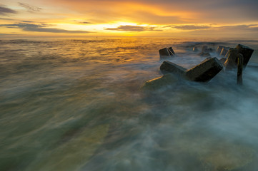 a sea breakwater breaking the waves at sunset