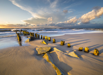 a sea breakwater breaking the waves at sunset - obrazy, fototapety, plakaty