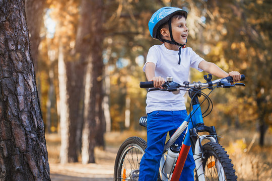 kid on a bicycle in the sunny forest. boy cycling outdoors in helmet
