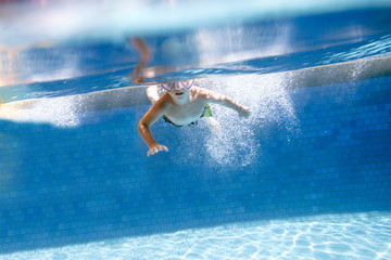 Little boy swims underwater swimming pool