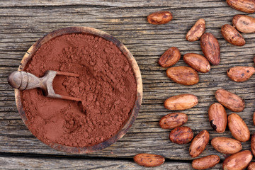 Cocoa powder in a bowl and beans on table