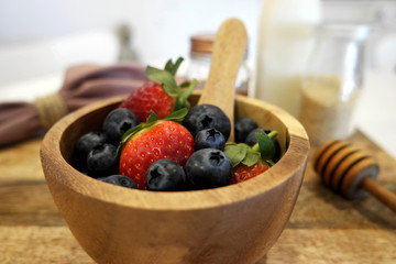 Strawberries and blueberries in a wooden bowl in a food preparation set up