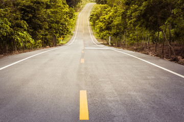Asphalt concrete road arcoss tropical forest along up to hill with sunlight shining, Concept of journey