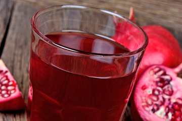 Pomegranate fruits with juice in a glass on table