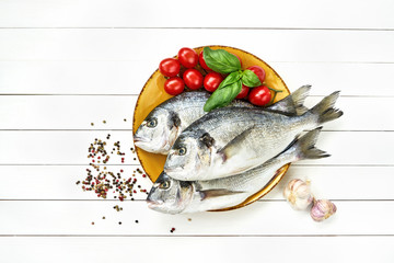 Raw dorado fish with vegetables on yellow plate on white wooden table. Top view, copy space