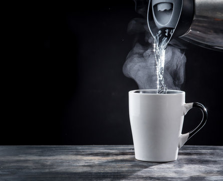 Fototapeta Pouring hot water into into a cup on a black background