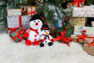 Cozy christmas background. Toy snowmen and presents under new year tree