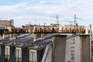 Fototapeta premium View on roofs of Paris with chimneys and antennas against blue sky.