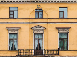 Several windows in a row and balcony on facade of urban apartment building front view, St. Petersburg, Russia