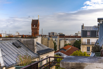 View on roofs of Paris with chimneys and antennas against blue sky.