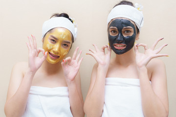 Beautiful smiling young Asian women having high quality and authentic pure gold facial mask and mud mask smiling and giving OK sign after skin treatment in spa salon