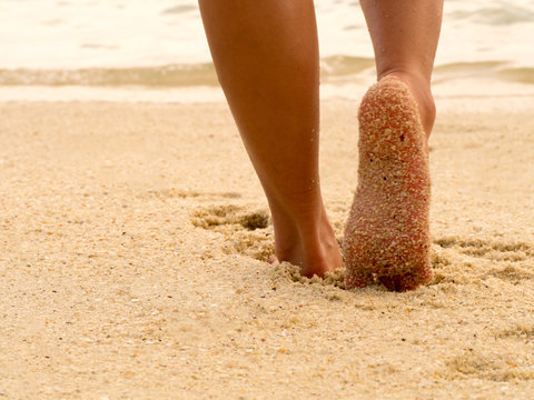 Sexy Asian women legs foot step on tropical sand beach. Walking female feet sand beach leaving footprints.