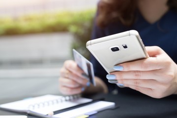 woman doing take notes accounting expense with  holding credit card and using phone. Online shopping purchase Sell or Payment.