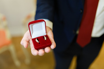 Red gift box with wedding rings in mens hands