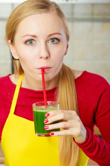 Woman in kitchen holding vegetable smoothie juice