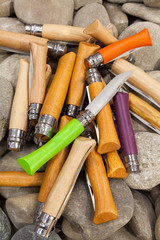 Folding knifes on background with round rocks