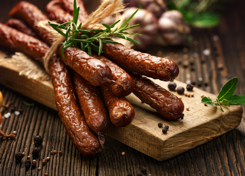 Kabanosy, polish sausages made of pork on a board with addition of fresh herbs and spices